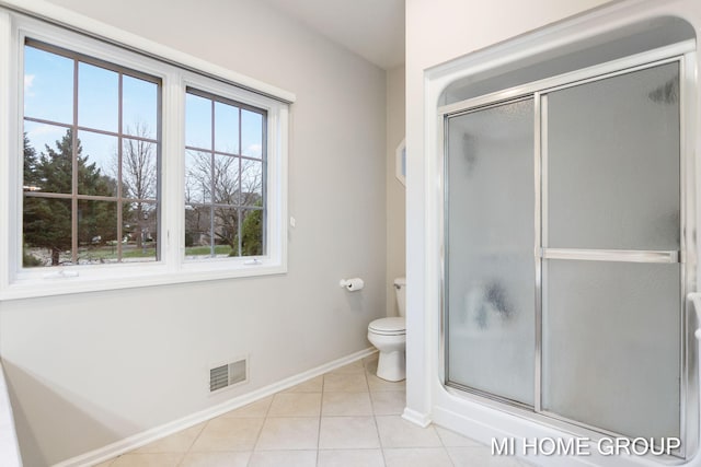 bathroom with tile patterned floors, toilet, and a shower with shower door