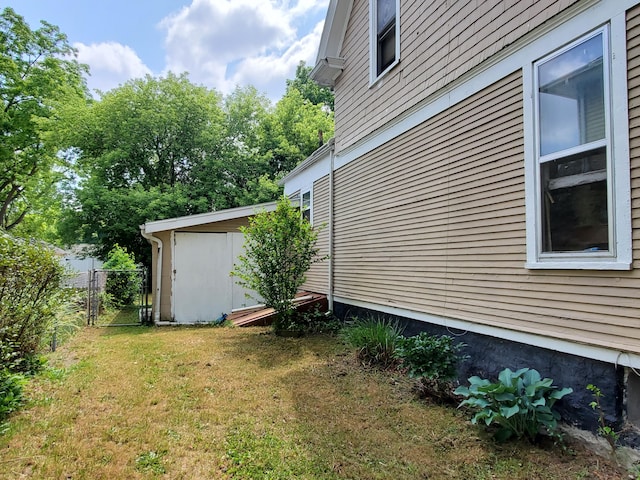 view of side of home with a lawn and a storage unit