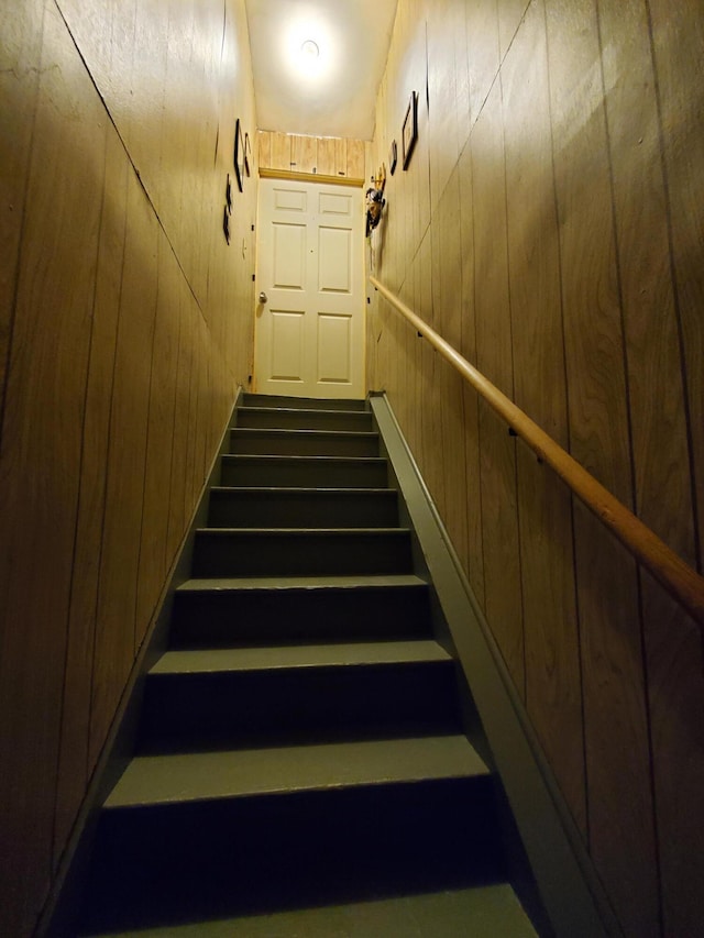 staircase featuring wooden walls