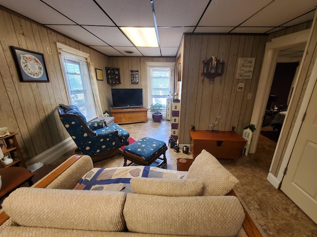 living room with a drop ceiling and wood walls