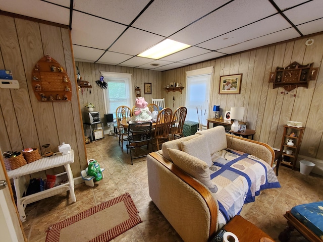 interior space with a paneled ceiling and wood walls