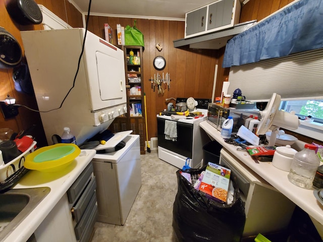 kitchen featuring stacked washer / drying machine, sink, white electric stove, and wooden walls