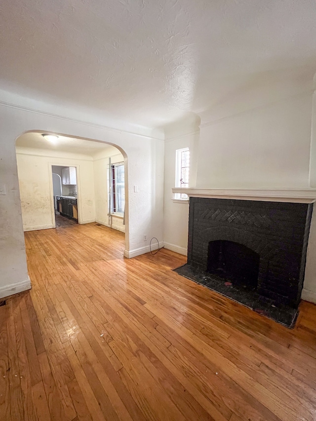 unfurnished living room featuring a brick fireplace and hardwood / wood-style floors