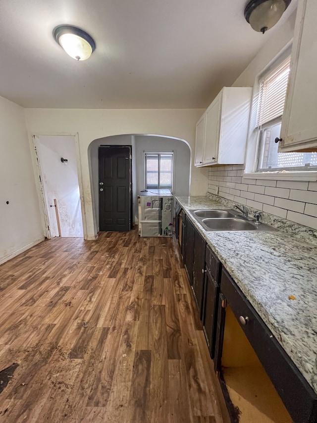 kitchen featuring tasteful backsplash, white cabinetry, sink, light stone countertops, and dark wood-type flooring