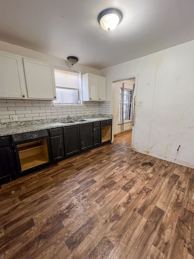 kitchen featuring hardwood / wood-style floors, white cabinetry, sink, decorative backsplash, and wall oven