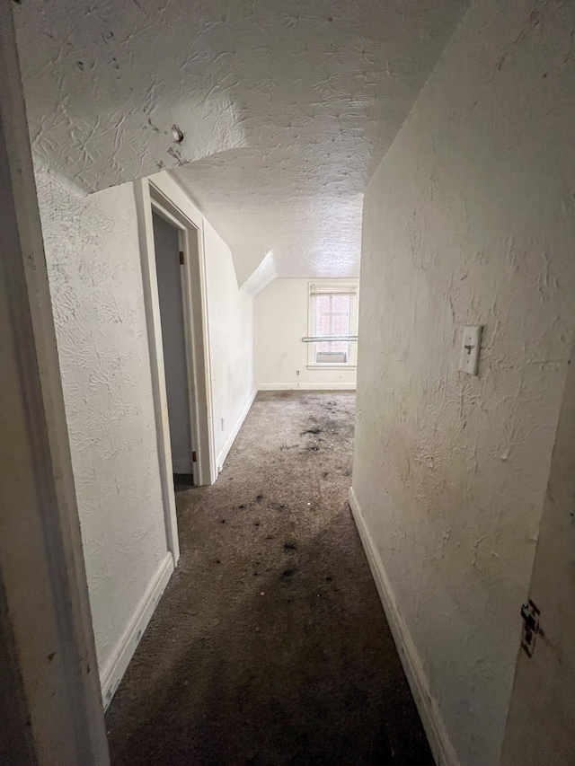 corridor featuring vaulted ceiling and a textured ceiling