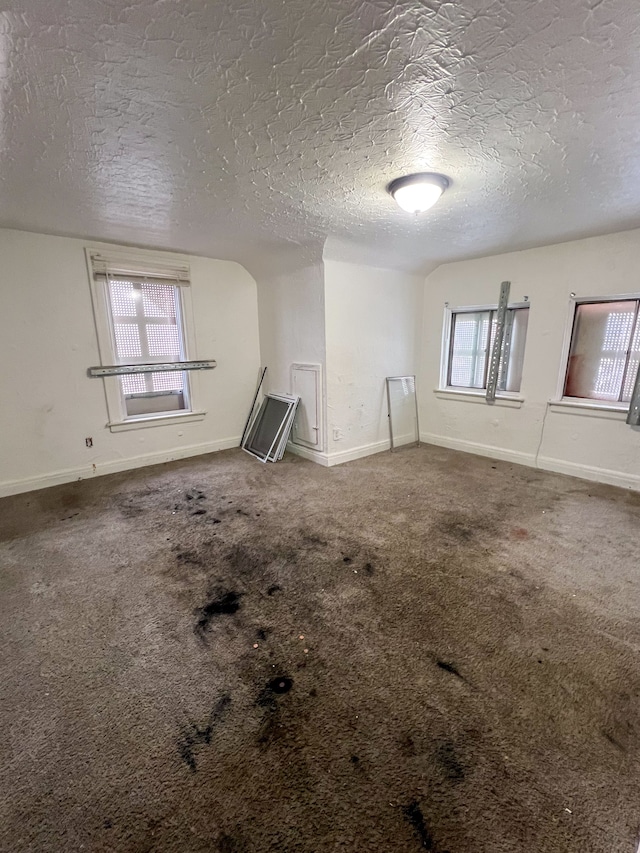 carpeted empty room with a textured ceiling