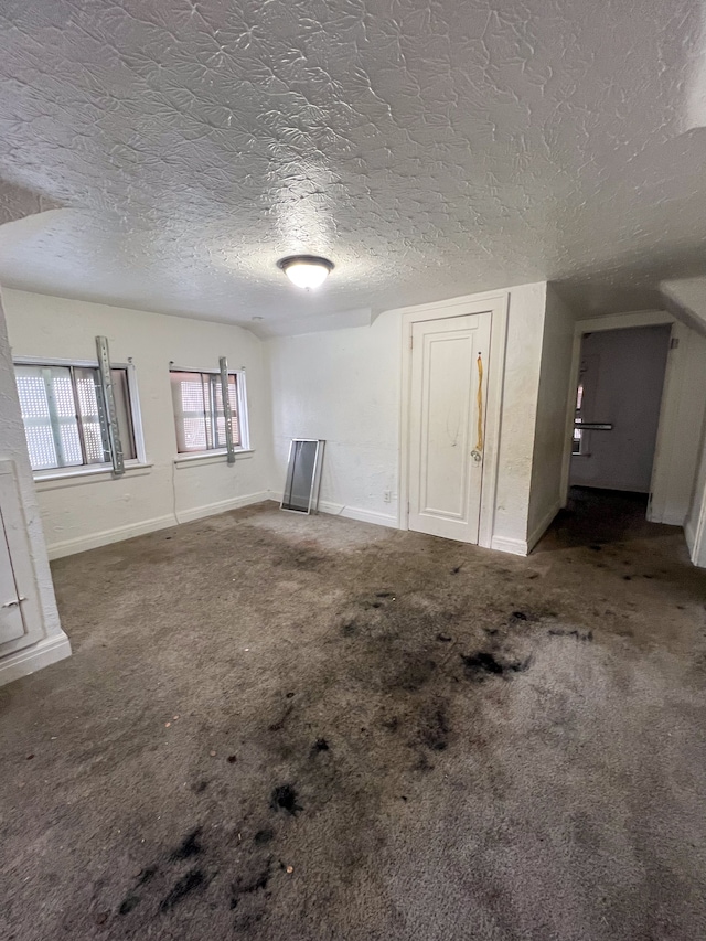 interior space with dark carpet and a textured ceiling