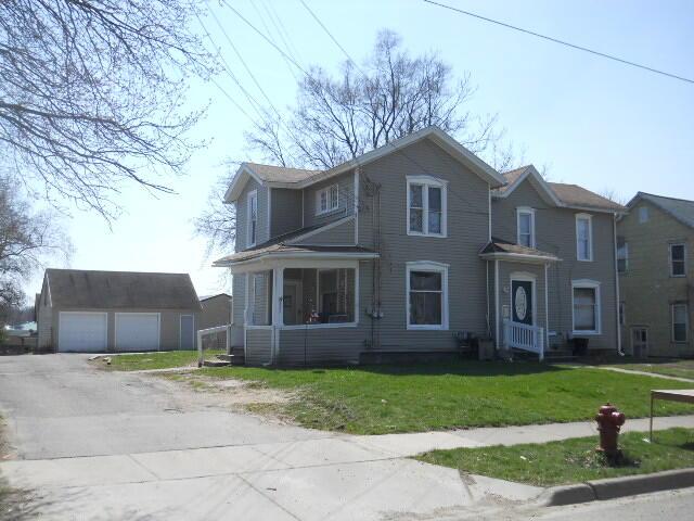 view of front property featuring a garage, an outdoor structure, a front yard, and covered porch