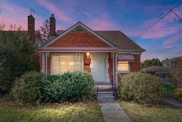 19723 Carrie St, Detroit, MI 48234 - view of front facade featuring brick siding, a chimney, and roof with shingles