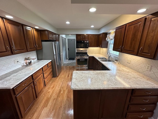 kitchen featuring decorative backsplash, sink, light hardwood / wood-style floors, and appliances with stainless steel finishes