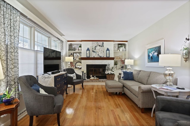 living room with a fireplace, light wood-type flooring, and built in shelves