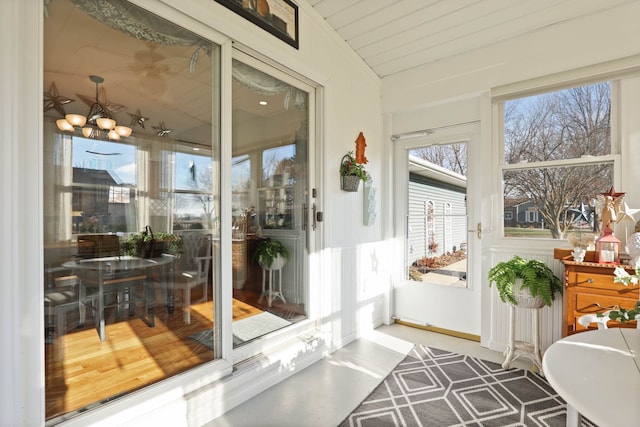 sunroom / solarium featuring a notable chandelier and vaulted ceiling