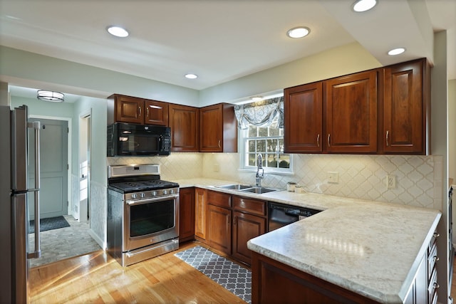 kitchen featuring sink, tasteful backsplash, light wood-type flooring, kitchen peninsula, and black appliances