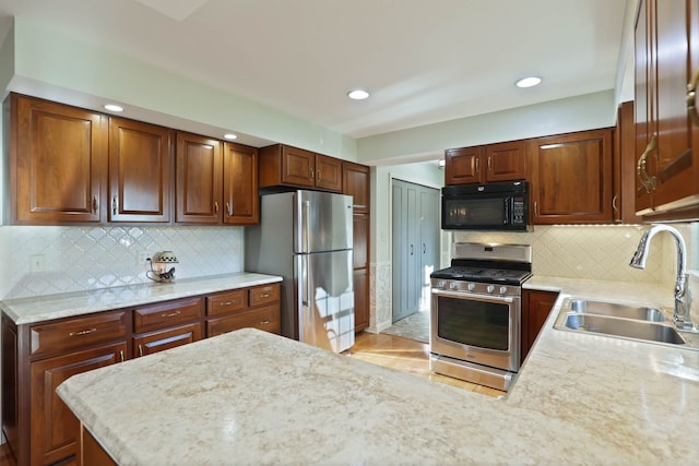 kitchen with stainless steel appliances, tasteful backsplash, sink, and light stone counters