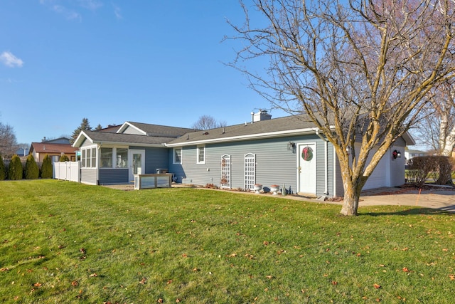 rear view of house featuring a sunroom and a lawn