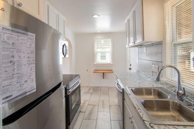 kitchen with backsplash, white cabinetry, sink, and appliances with stainless steel finishes