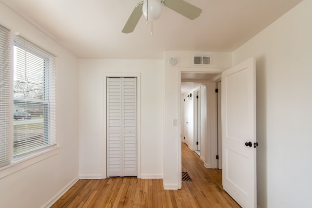 unfurnished bedroom with light wood-type flooring, a closet, and ceiling fan