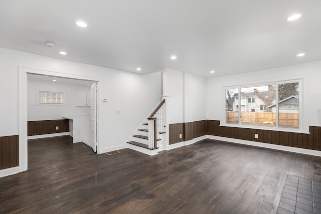 spare room with wood walls and dark wood-type flooring