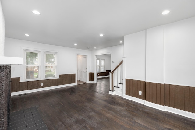 unfurnished room featuring a fireplace, wood walls, and dark wood-type flooring