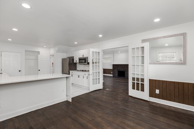 kitchen featuring french doors, wooden walls, dark hardwood / wood-style flooring, white cabinetry, and stainless steel appliances