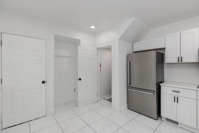 kitchen with stainless steel fridge and white cabinetry