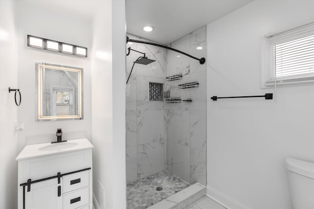 bathroom with a tile shower, vanity, and toilet