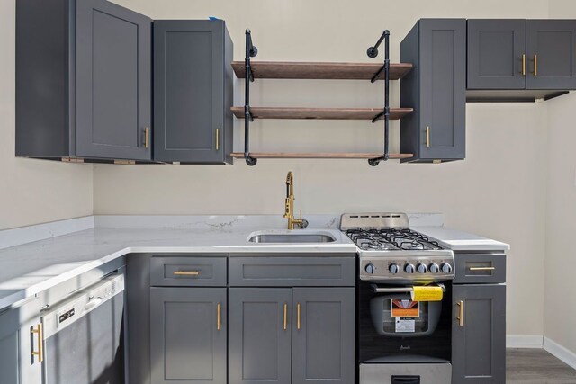 kitchen with light stone countertops, appliances with stainless steel finishes, gray cabinetry, and sink