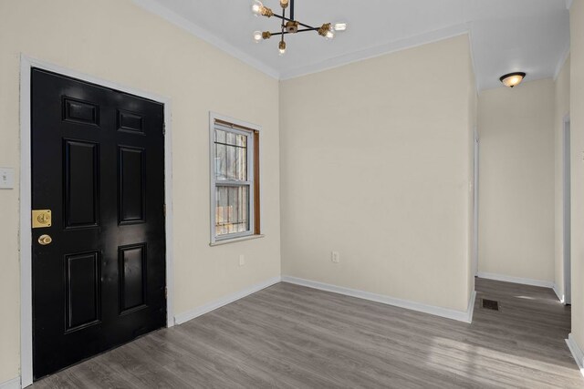 foyer entrance with a notable chandelier, crown molding, and light hardwood / wood-style flooring