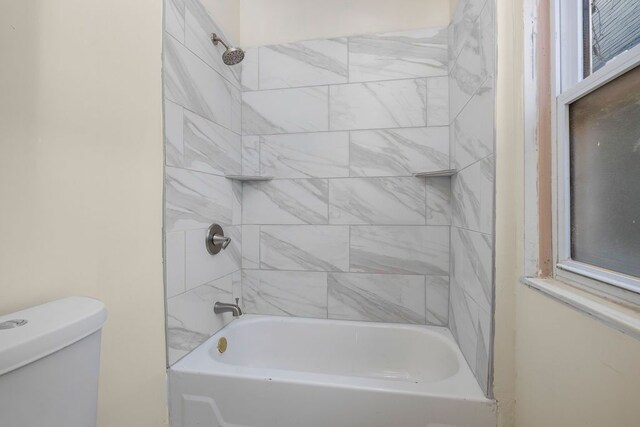 bathroom with tiled shower / bath combo and toilet