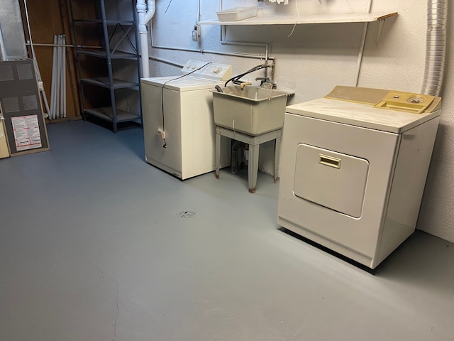 laundry area featuring washing machine and dryer, heating unit, and sink