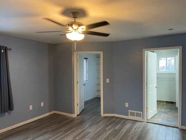 unfurnished bedroom with ceiling fan, dark wood-type flooring, and a spacious closet