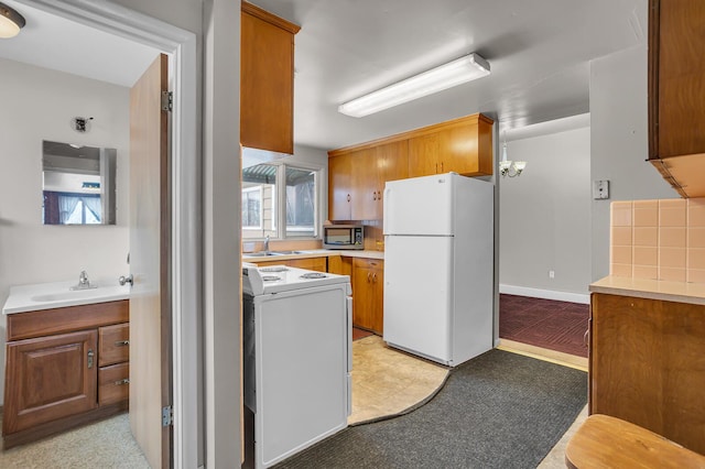 kitchen featuring decorative backsplash, white fridge, range, and sink