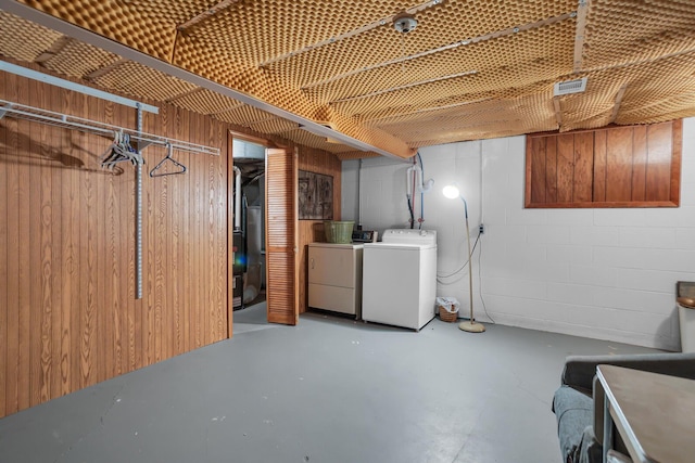 basement featuring wooden walls and washing machine and clothes dryer