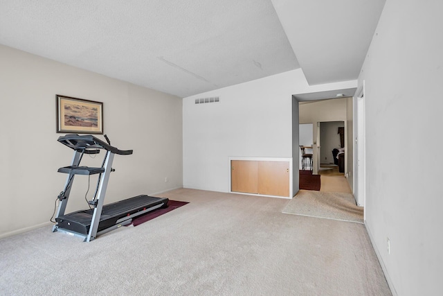 workout room with a textured ceiling and light carpet