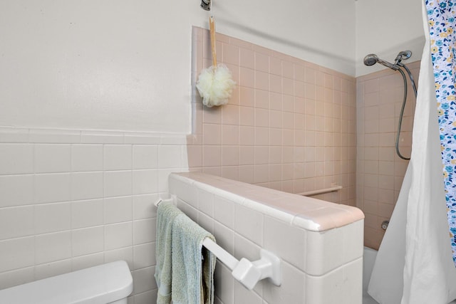 bathroom featuring toilet, tile walls, and shower / tub combo