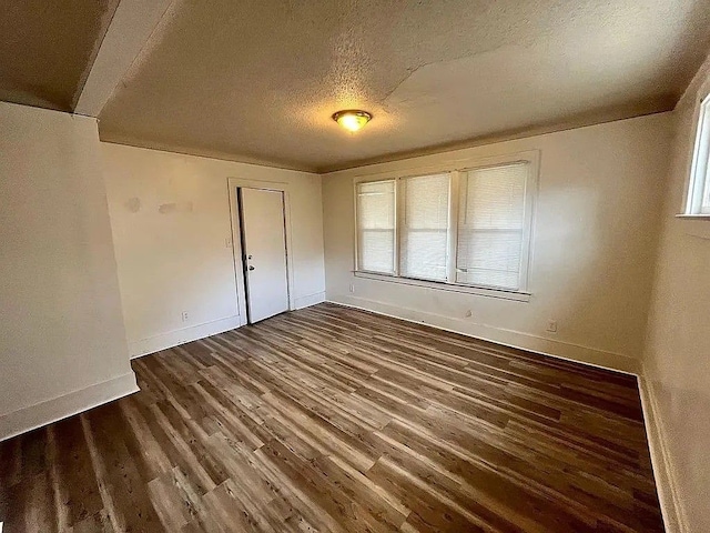 unfurnished bedroom with a textured ceiling and dark wood-type flooring