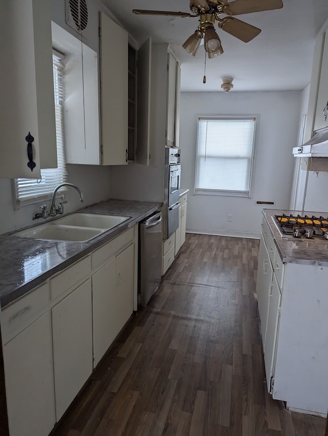 kitchen with appliances with stainless steel finishes, dark hardwood / wood-style floors, white cabinetry, and sink