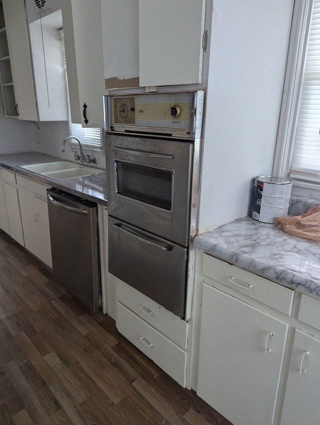 kitchen with wall oven, white cabinetry, stainless steel dishwasher, and sink