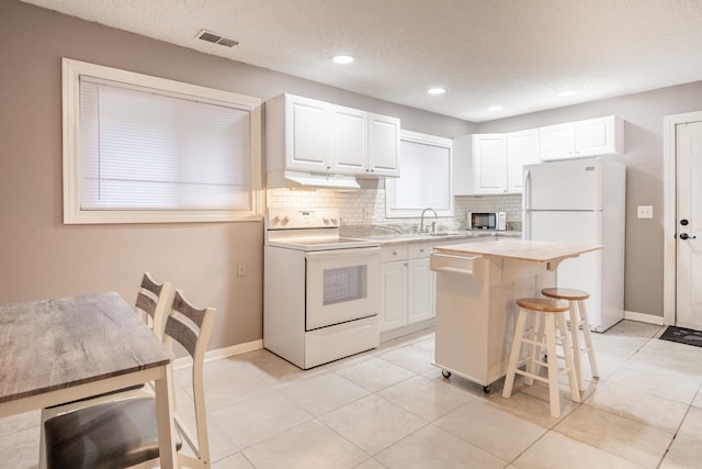 kitchen with white cabinetry, range with electric cooktop, a center island, a kitchen breakfast bar, and white refrigerator