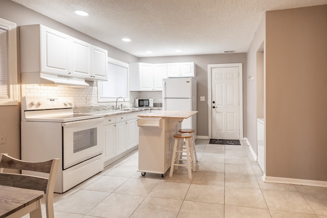 kitchen featuring a breakfast bar, sink, electric range, white cabinets, and a center island