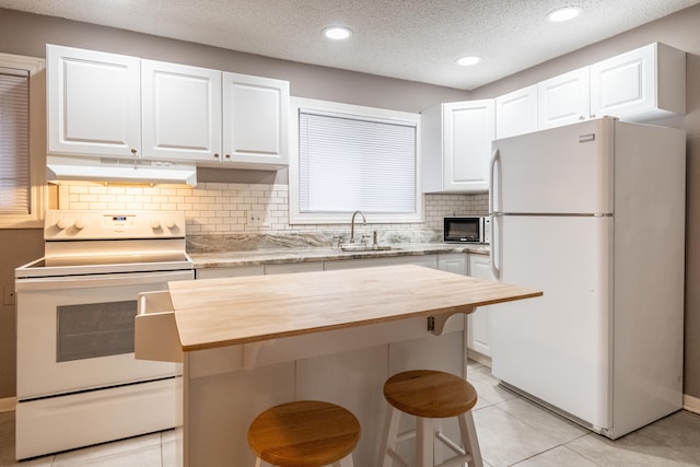 kitchen with a kitchen breakfast bar, white cabinets, and white appliances