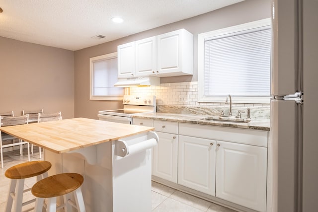 kitchen with a center island, sink, white electric stove, a breakfast bar area, and white cabinets