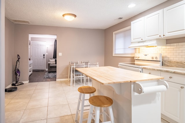 kitchen featuring a kitchen bar, white cabinets, a kitchen island, range with electric stovetop, and light tile patterned flooring