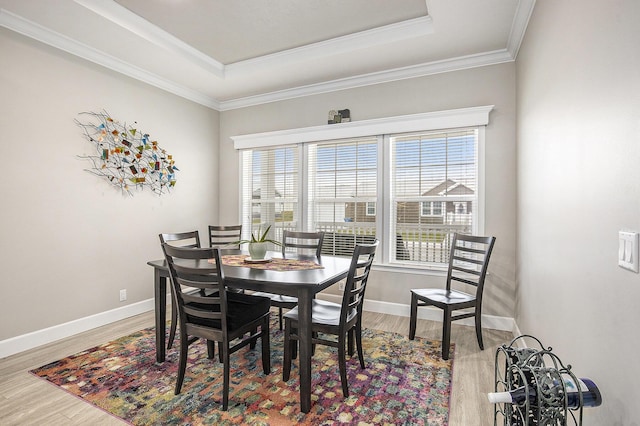 dining area with hardwood / wood-style flooring, a raised ceiling, ornamental molding, and a wealth of natural light