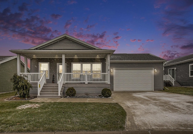 view of front of home with a porch, a yard, and a garage