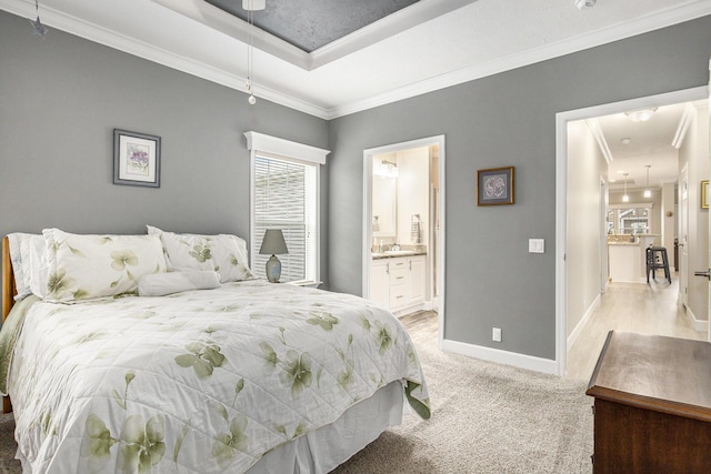 bedroom featuring light carpet, connected bathroom, a raised ceiling, and crown molding