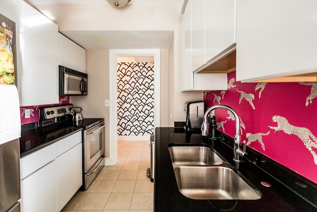 kitchen with light tile patterned floors, white cabinetry, sink, and appliances with stainless steel finishes