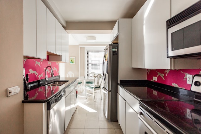 kitchen with light tile patterned flooring, appliances with stainless steel finishes, white cabinetry, and sink