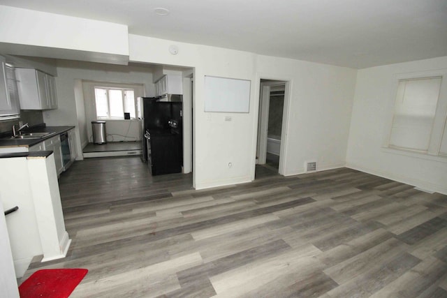 kitchen featuring sink, black fridge, stainless steel dishwasher, dark hardwood / wood-style floors, and white cabinets